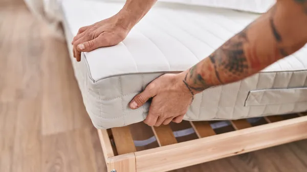 1761236231-young-man-holding-mattress-bedroom (1)